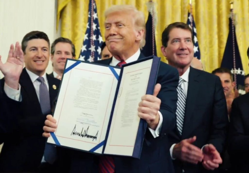 President Donald Trump holding up signed GENIUS Act in the White House.